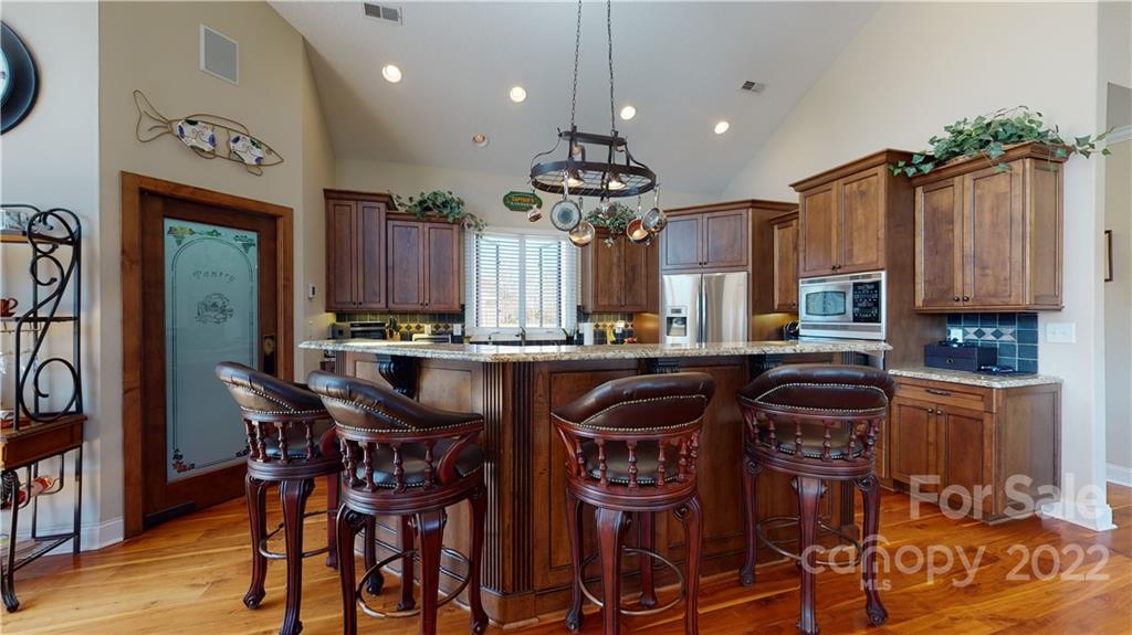 3908 Thompson Road Lancaster, SC 29720 - Photo 19 of 36 a kitchen with stainless steel appliances granite countertop a stove top oven a sink a dining table and chairs with wooden floor