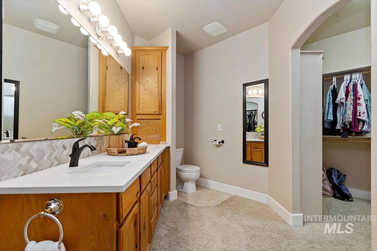 10462 West Lanktree Gulch Road Star, ID 83669 - Photo 21 of 48 Bathroom vanity featuring a single sink, light-toned countertop, wood-finish cabinetry, and a full-width mirror with overhead light fixture