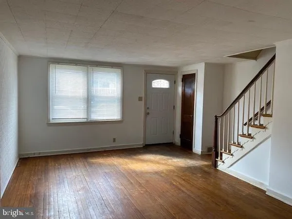 a view of an empty room with wooden floor and stairs