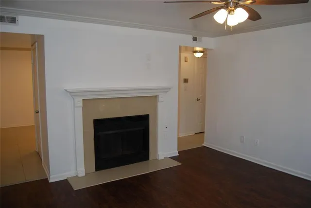 an empty room with wooden floor a ceiling fan and a fireplace