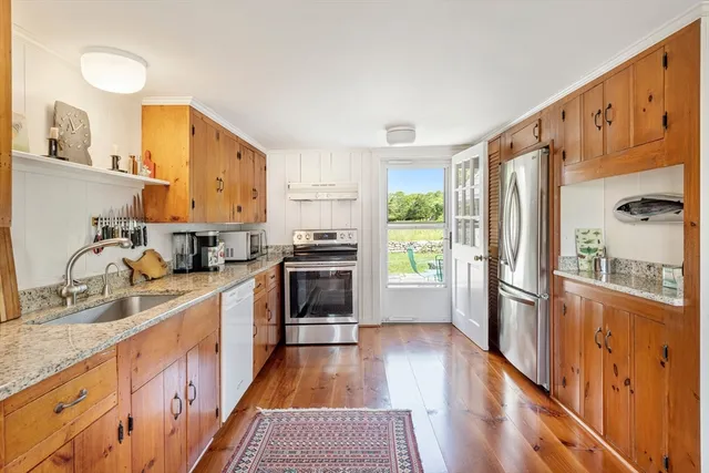 a kitchen with stainless steel appliances granite countertop a sink cabinets and wooden floor