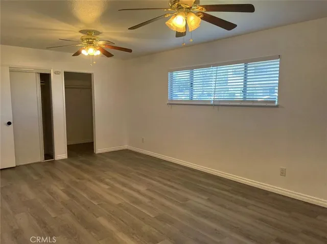 an empty room with wooden floor fan and window