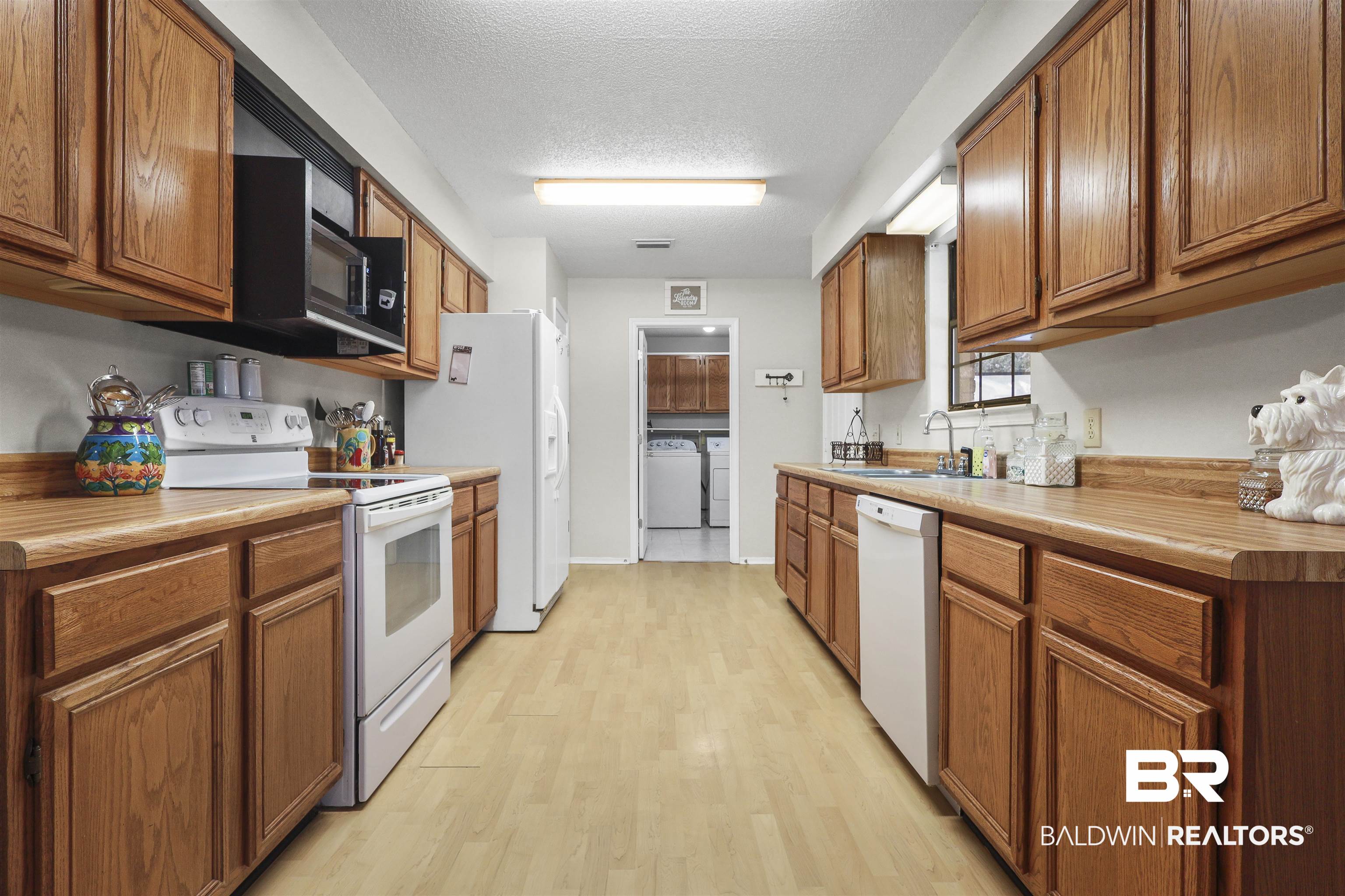 507 West Amanda Avenue Foley, AL 36535 - Photo 17 of 23 Kitchen featuring light hardwood / wood-style floors, a textured ceiling, washer and dryer, sink, and white appliances