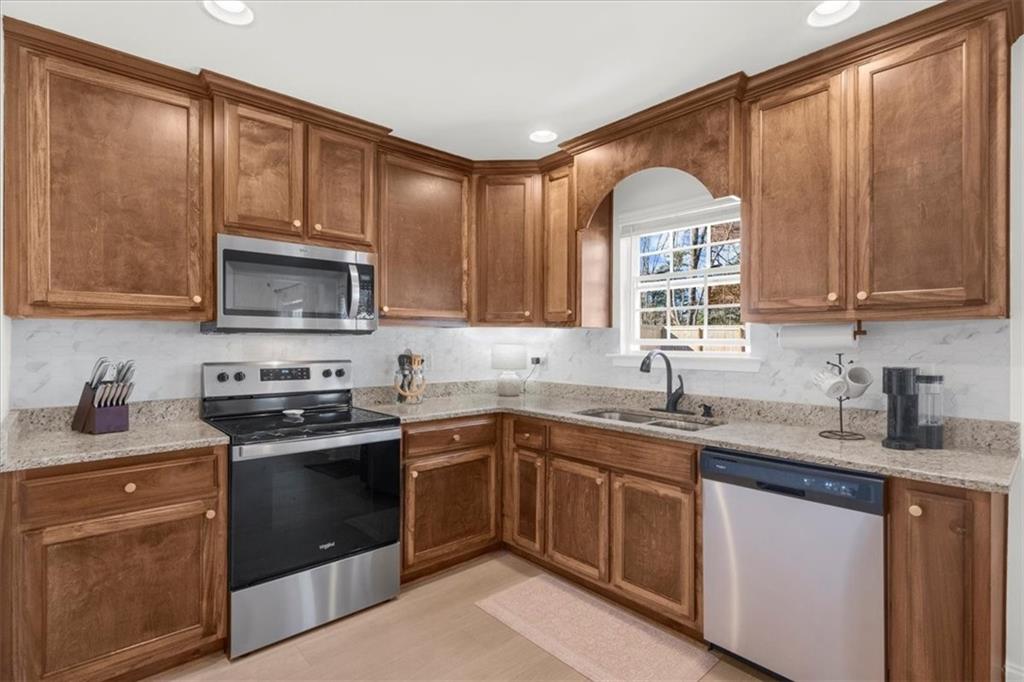 5413 Stepstone Way Gainesville, GA 30506 - Photo 11 of 36 a kitchen with stainless steel appliances granite countertop a sink stove microwave and cabinets
