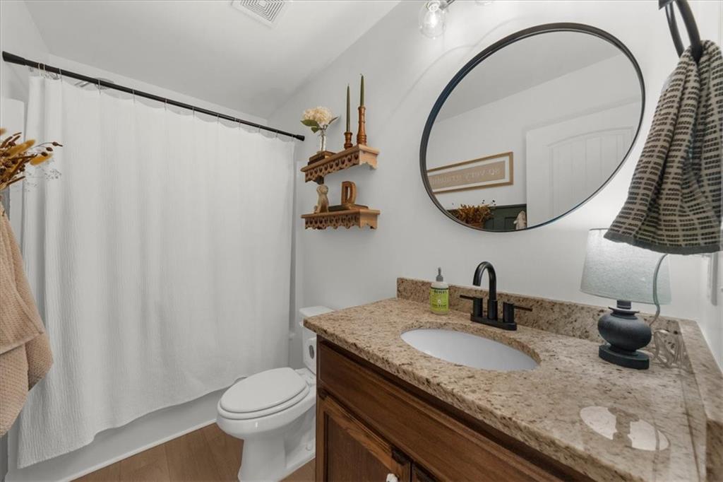 5413 Stepstone Way Gainesville, GA 30506 - Photo 23 of 36 a bathroom with a granite countertop sink a toilet and a mirror