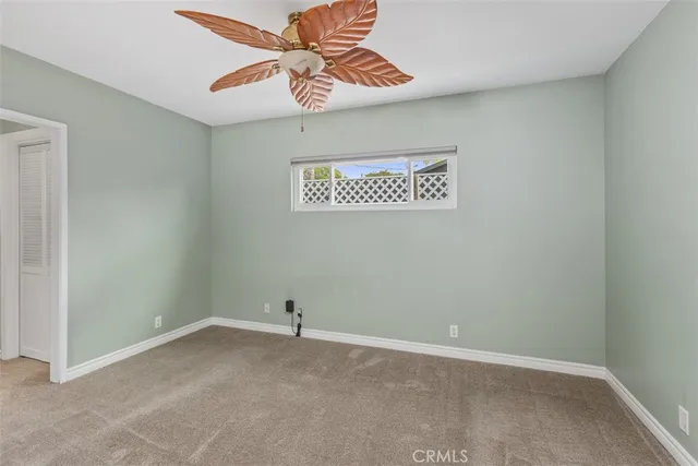 an empty room with a fan & cabinets