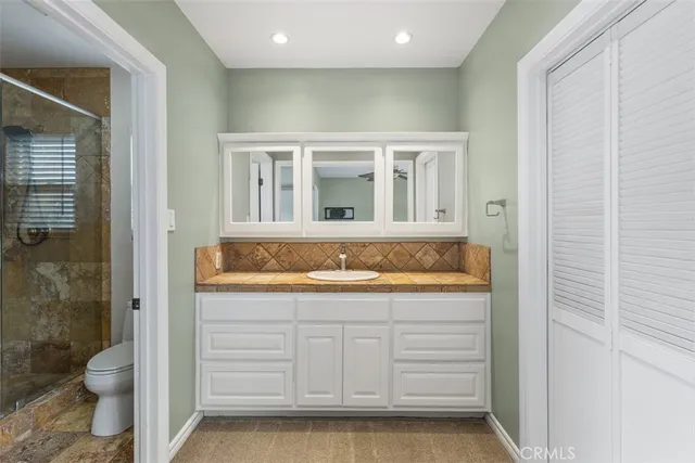 a bathroom with a granite countertop sink mirror vanity and toilet