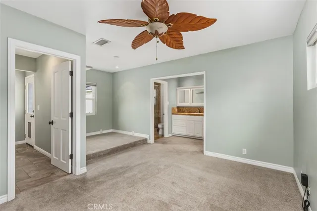 a view of a room with a ceiling fan and a carpet