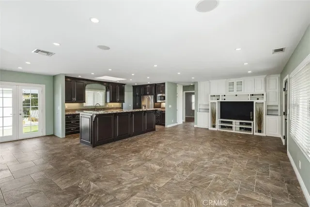 a large white kitchen with kitchen island a sink a counter top stainless steel appliances and a couch