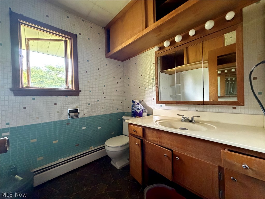 3246 Tabor Ridge Road Northeast Mineral City, OH 44656 - Photo 10 of 29 Bathroom featuring a wood-finish vanity with an integrated sink, a mirrored medicine cabinet with integrated lighting, and mosaic wall tiling