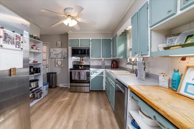 a kitchen with stainless steel appliances a stove a sink dishwasher and a refrigerator with wooden floor