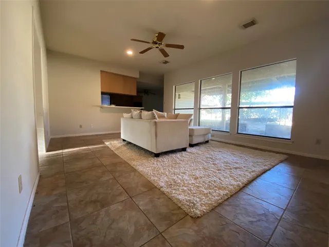 a living room with a rug and a ceiling fan