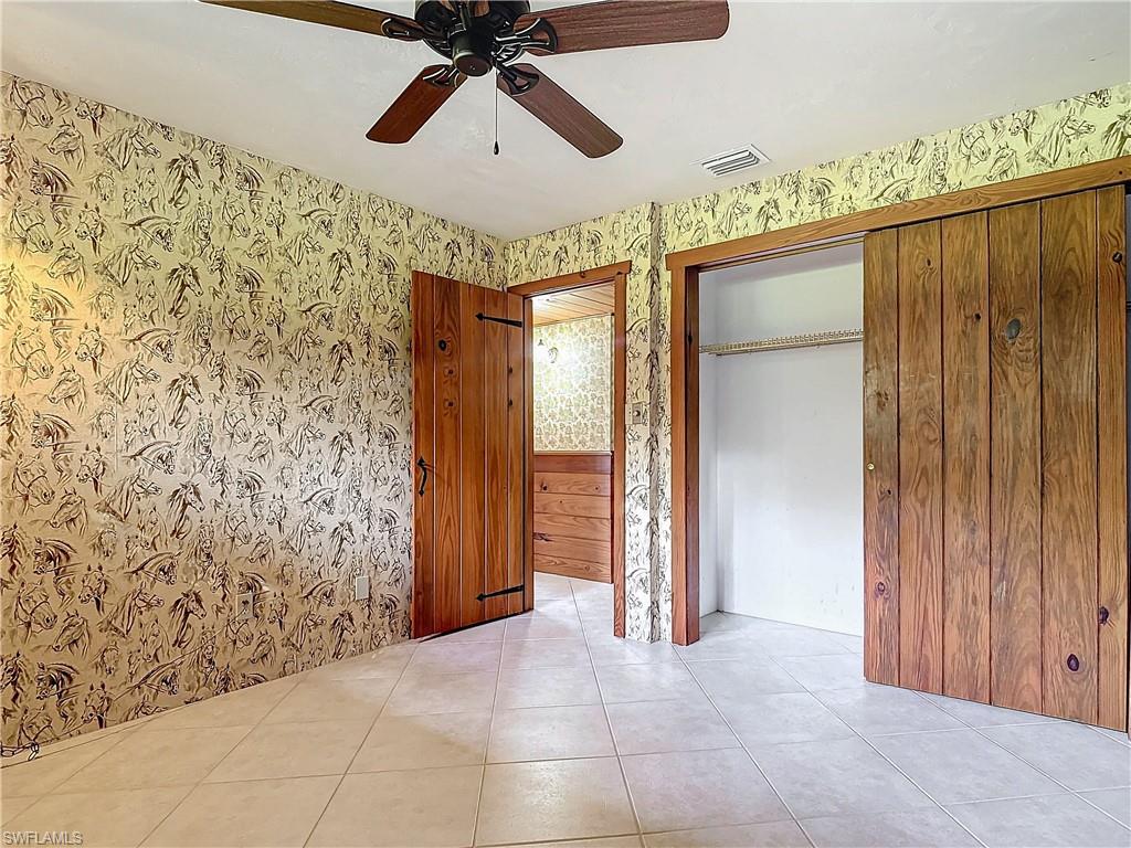 3550 11th Avenue Southwest Naples, FL 34117 - Photo 21 of 35 Unfurnished Guest bedroom 1 with ceiling fan, a closet, light tile patterned floors, and wood walls