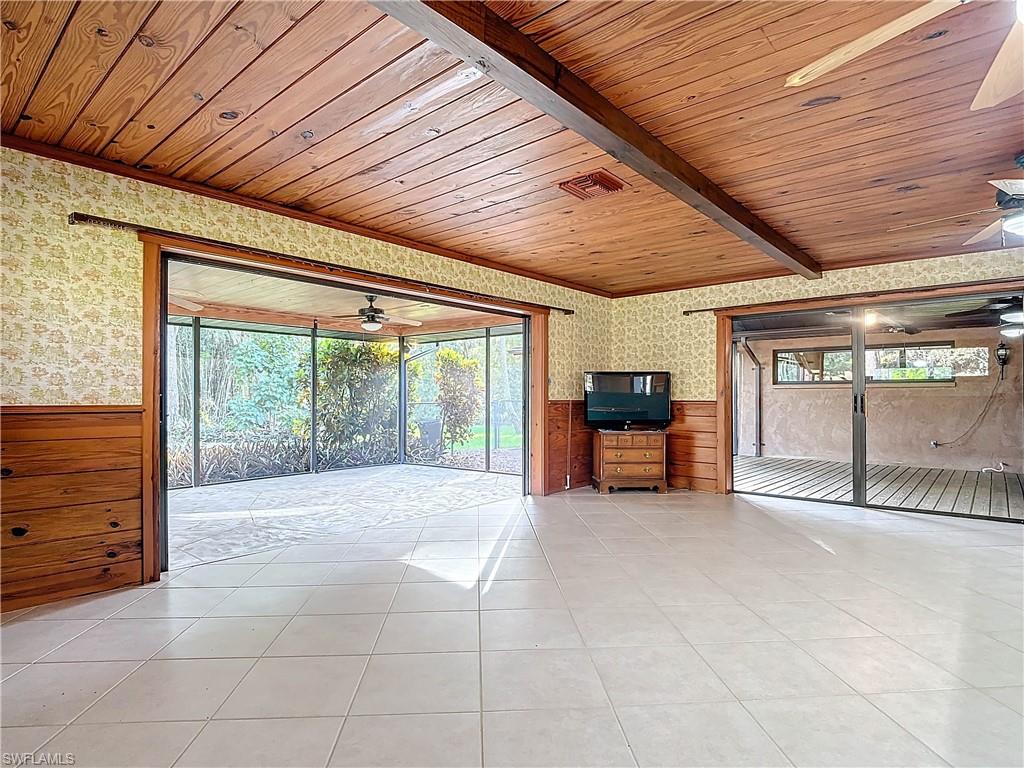 3550 11th Avenue Southwest Naples, FL 34117 - Photo 8 of 35 Living room featuring wooden ceiling, beamed ceiling, a healthy amount of sunlight, and wood walls