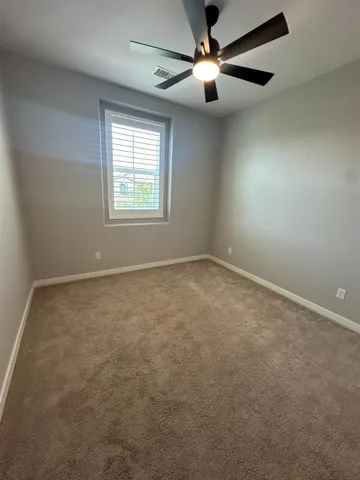 an empty room with a window and a fan