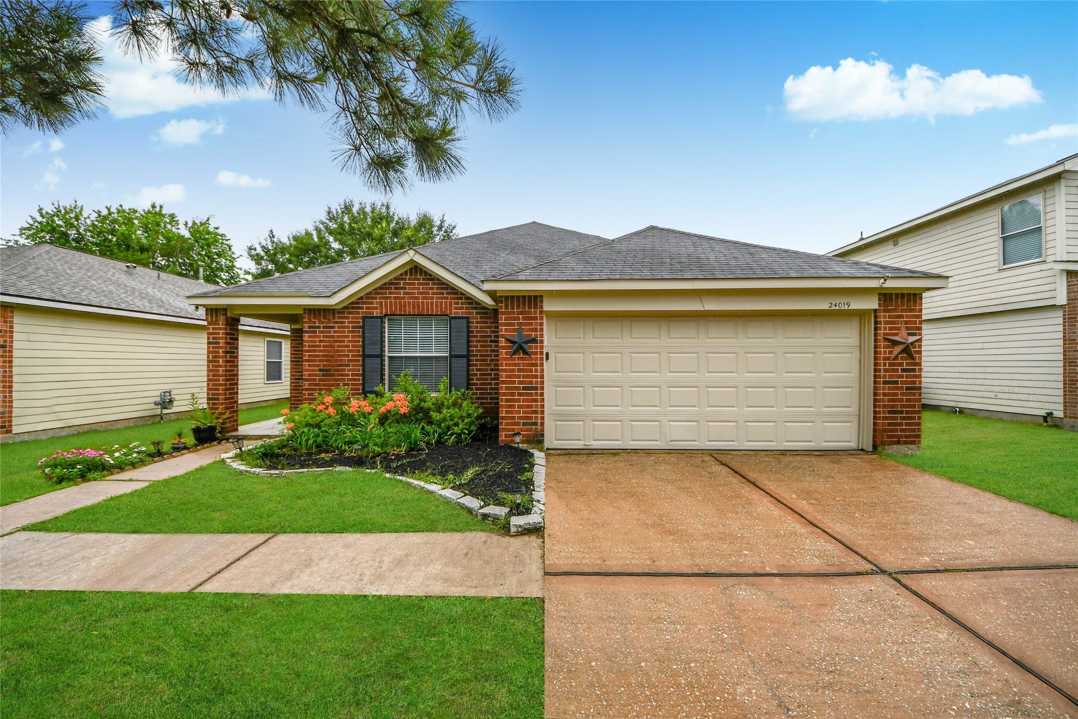 24019 Kingbriar Drive Spring, TX 77373 - Photo 7 of 41 A focused frontal image emphasizing the textural details of the brick exterior, detailed landscaping with flowering plants, and the home's lovely architecture under a bright, sunny sky.