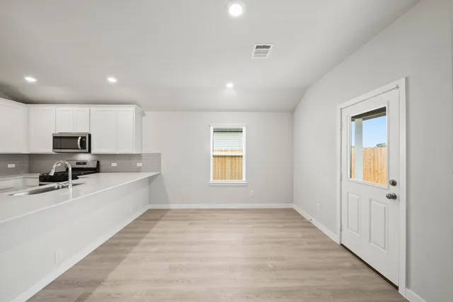 a large white kitchen with wooden floor and a window