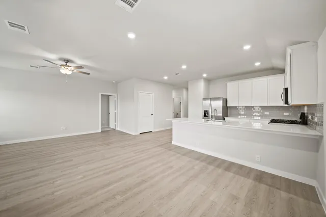 a large white kitchen with kitchen island a sink wooden floor and a chandelier