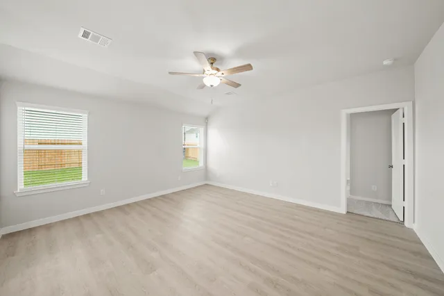 an empty room with a window and a ceiling fan