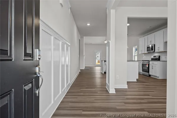 a kitchen with stainless steel appliances granite countertop a stove a sink dishwasher a refrigerator and white cabinets with wooden floor