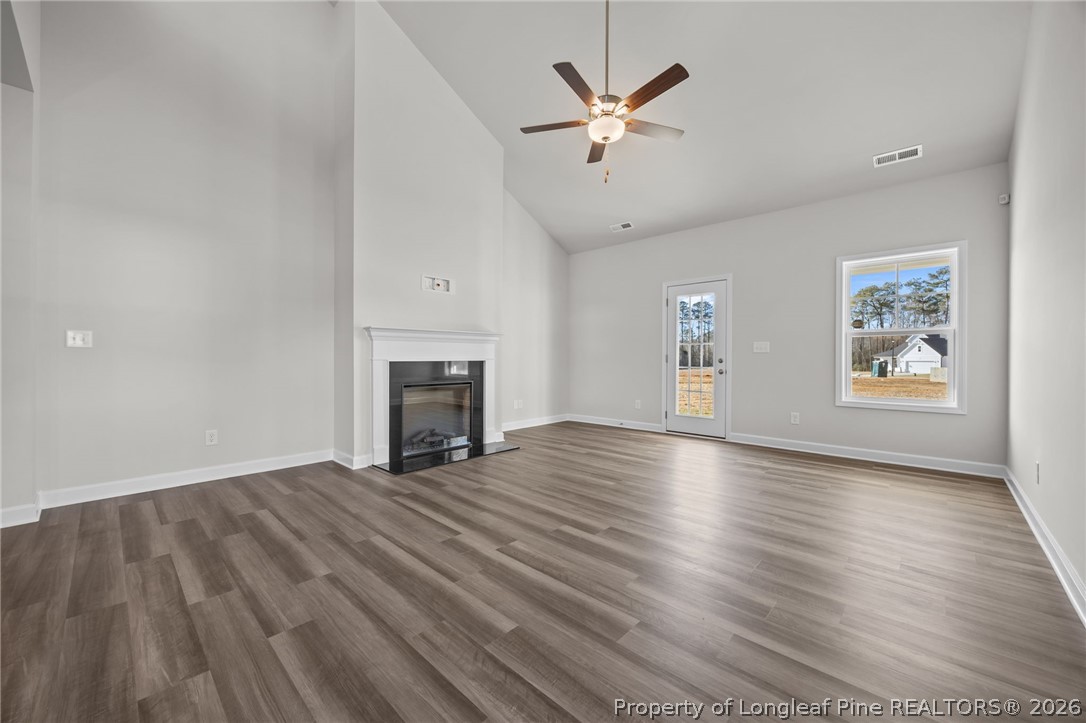 287 Elijah Way Vass, NC 28394 - Photo 22 of 49 an empty room with wooden floor fireplace and windows