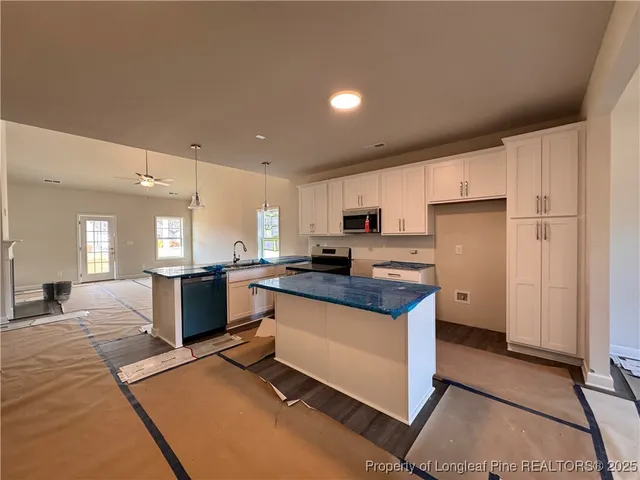 a kitchen with stainless steel appliances granite countertop a stove a sink a refrigerator and white cabinets with wooden floor