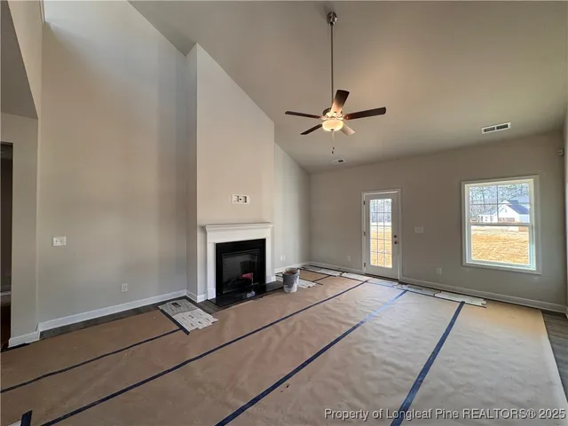 a living room with a fireplace furniture a ceiling fan and a window