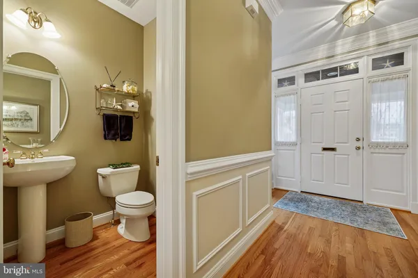 a view of a hallway with wooden floor and a bathroom
