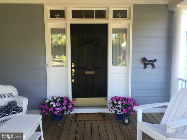 a view of a house with potted plants and a bench in front of it