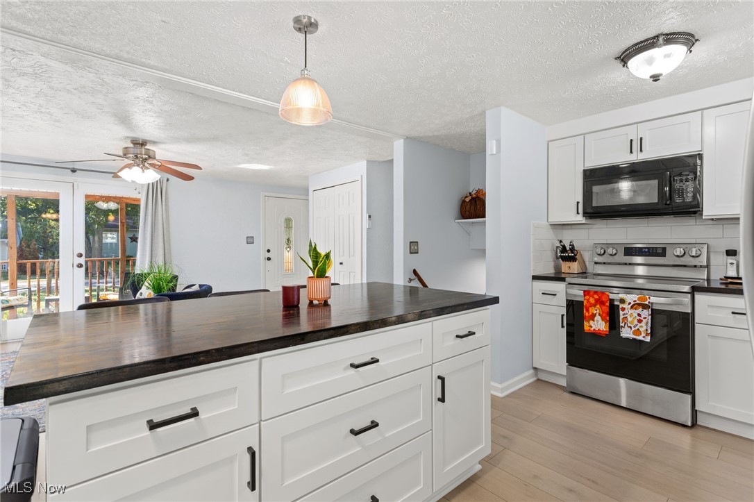 667 High Bridge Road Vermilion, OH 44089 - Photo 8 of 30 Kitchen with electric stove, white cabinets, black microwave, light wood-style floors, and pendant lighting