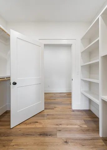 a view of an empty walk in closet with wooden floor