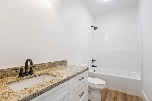 a bathroom with a granite countertop sink toilet and a mirror
