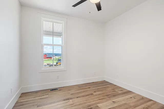 an empty room with wooden floor and window