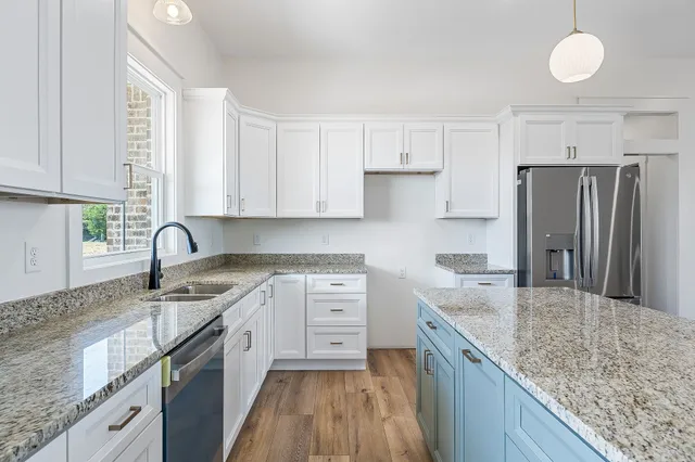 a kitchen with stainless steel appliances granite countertop a sink stove refrigerator and cabinets