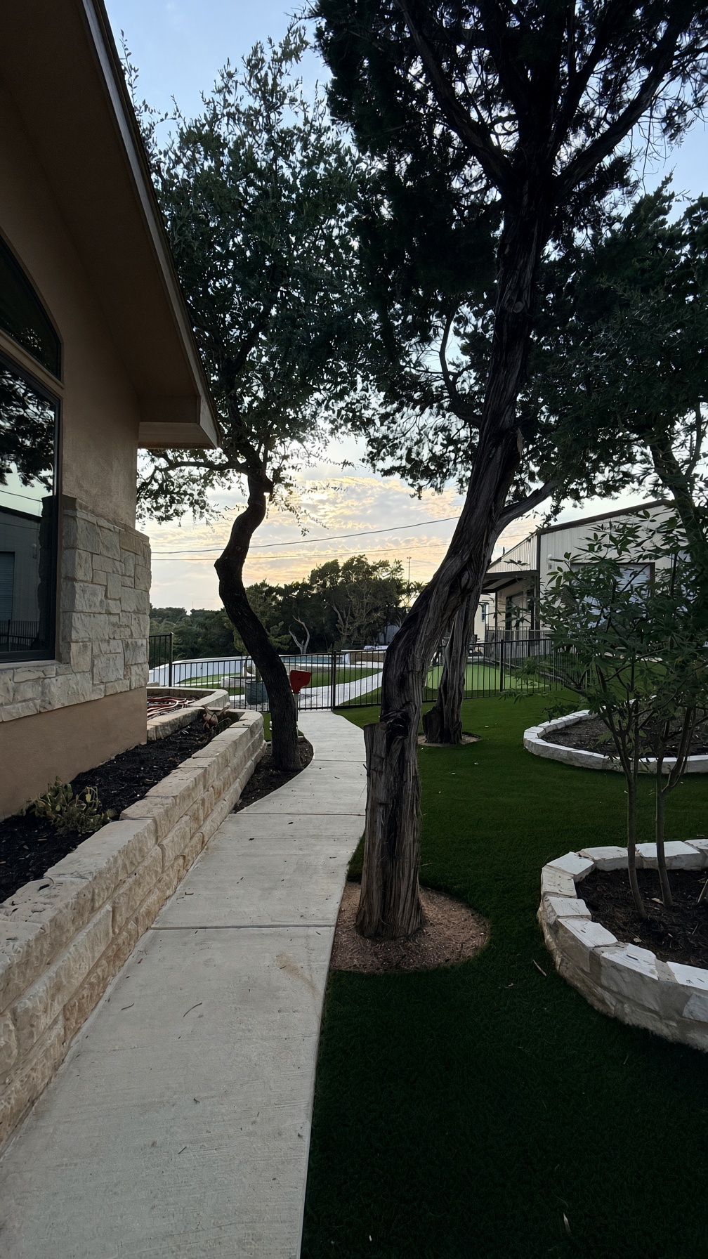 19005 White Rim Trail Jonestown, TX 78645 - Photo 2 of 39 Concrete walkways wind past stone garden beds and manicured turf under mature shade trees.