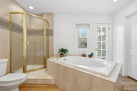 a bath room with a toilet a bath tub and a shower