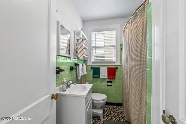 a view of a hallway with wooden floor and a bathroom