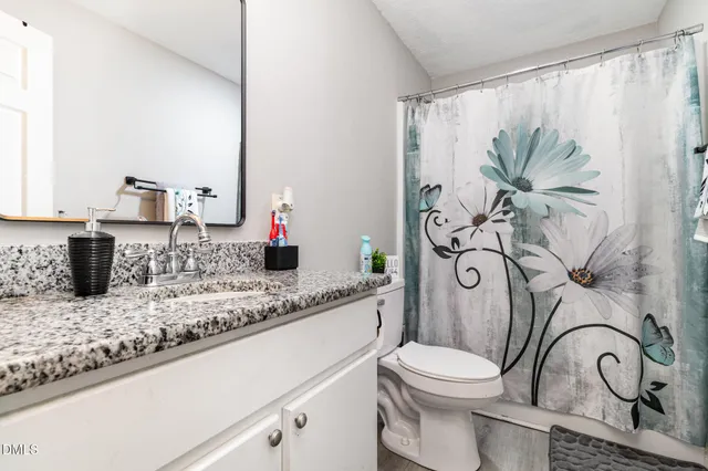 a bathroom with a granite countertop sink a toilet and mirror
