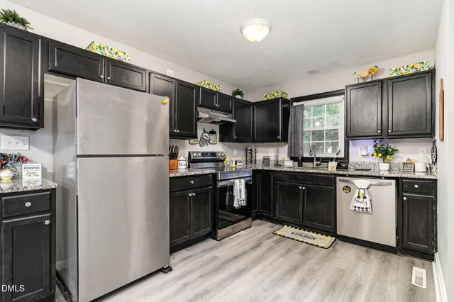 a kitchen with granite countertop stainless steel appliances a refrigerator cabinets a sink and a window