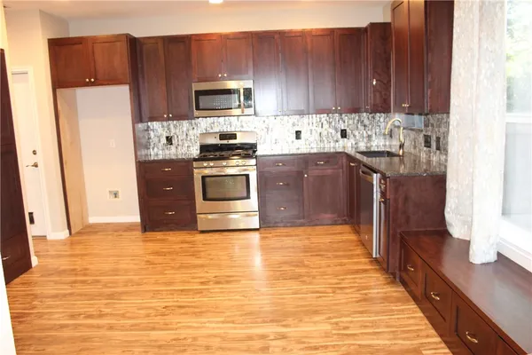 a kitchen with stainless steel appliances granite countertop a refrigerator stove top oven and sink
