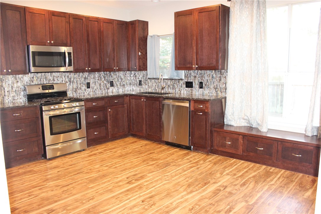 7801 Varcella Trail Austin, TX 78729 - Photo 5 of 26 a kitchen with stainless steel appliances granite countertop a stove a sink dishwasher and a microwave oven with cabinets