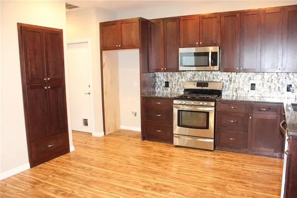 a kitchen with stainless steel appliances granite countertop a stove a refrigerator and a microwave