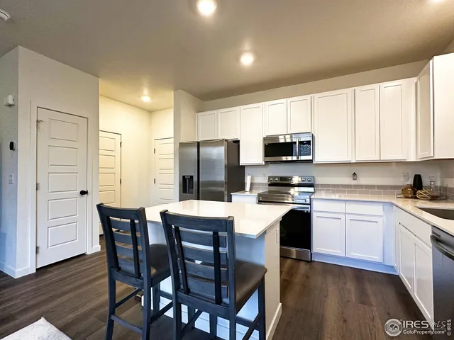 a kitchen with stainless steel appliances a stove a sink dishwasher a refrigerator with a dining table and chairs