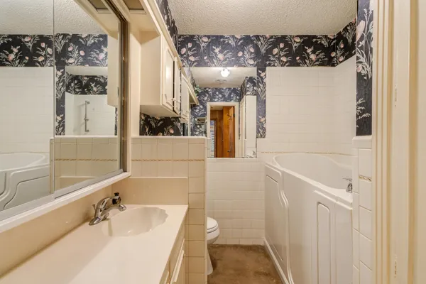 a bathroom with a bathtub a sink and a large mirror