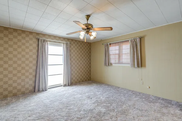 an empty room with windows and fan