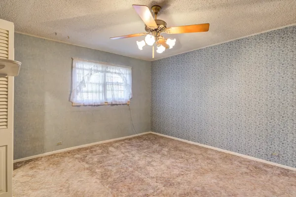 an empty room with windows and chandelier fan