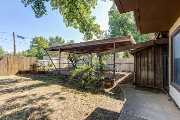 a view of backyard with seating space and wooden fence