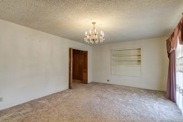 an empty room with chandelier and windows