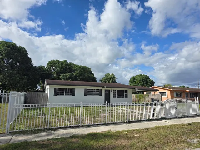 a view of house with a big yard and large trees