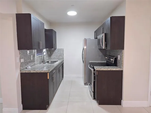a kitchen with stainless steel appliances granite countertop a sink and a refrigerator